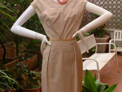 Il "Safari", sofisticato capo in bourette di lino beige con scollo asimmetrico, manica con taglio america (cio� poco sotto la spalla) e pieghe create con ricami e  sulla parte centrale della gonna